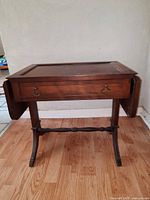 Front view of walnut finish side table with drop leaves folded down