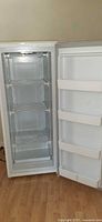 Open upright freezer showing shelves and door bins