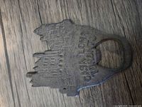 Front view of cast iron Casa Loma castle bottle opener showing raised architectural details and "Casa Loma" text