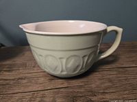 side view showing green exterior, handle, spout and motif