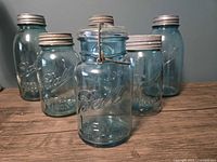 Front view of six blue Ball jars showing embossing and lid types
