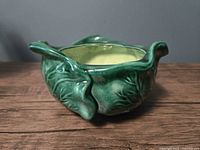 Three-quarter view of green ceramic cabbage planter showing leaf texture and interior