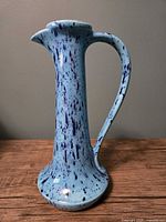 Front view of tall blue splatter glaze ceramic pitcher vase showing handle and spout