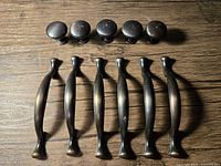 Five round knobs and six pulls displayed on wood surface
