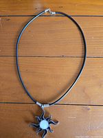 Entire necklace laid flat showing white-center sunburst pendant