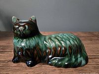 Front-right view of glazed ceramic long-haired cat figurine on wooden surface