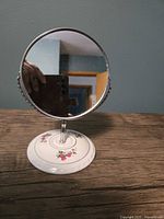Front view of round swivel mirror on ceramic floral base