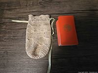 Deck in red slipcase beside crocheted bag