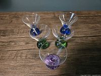 Five mini martini glasses angled, bases visible in green, blue, purple