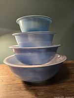 Side view of four stacked blue glass bowls showing graduated sizes and colors