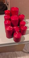 Front view of 11 red pillar candles showing varying heights