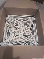 Box nearly full of white plastic hangers