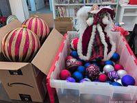 Bin with assorted ornaments and angel topper next to box of large pink/gold ornaments