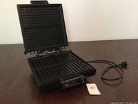 Appliance open displaying non-stick waffle plates and power cord