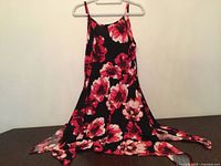 Front view of black floral sundress hanging on hanger