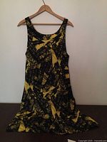 Front view of black and yellow abstract print sundress on hanger