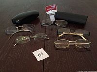 All five pairs of eyeglasses and two cases arranged on table