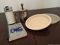 Group shot of all items: Braun grinder, stainless frother, plastic dish with lid, spiral cookbook