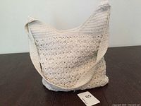 Front view of white crocheted shoulder bag showing overall design and strap