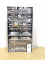 Front view of grey plastic drawer cabinet showing multiple drawers filled with hardware