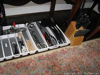 Tray of kitchen utensils with various black plastic spoons, spatulas, and metal tools.