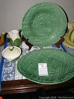 Overview of two green majolica style platters, white sugar bowl with lid, and green/white creamer jug on table