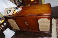 Front view of vintage wood console stereo The Fisher Electra model with wood finish and fabric speaker grills