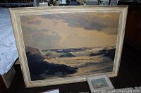 Full view of the framed art print showing the ocean and rocky shore scene under cloudy sky