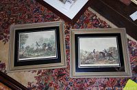 Two framed Carle Vernet hunting scene prints displayed on a patterned carpet showing both prints side by side.