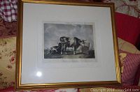 Framed lithograph showing two cows in a rural landscape, with gold wood frame and white matting