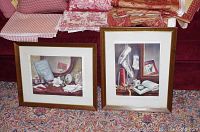 Two framed still life art prints displayed on a carpeted floor with fabric in the background, showing both artworks in the lot.