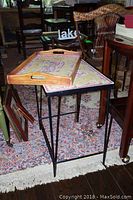 View of rectangular mosaic style table with wrought iron legs next to the decorative wooden tray on top of it, showing dimensions relative to surrounding furniture.