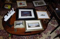 Seven framed art prints arranged on a wooden table including the Melk Cathedral etching and Starry Night print.