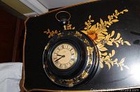 Photo of vintage clock showing full clock and case with floral decorations.
