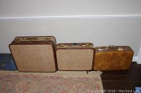 Three vintage beige woven textured suitcases with brown trim next to a tan patina suitcase