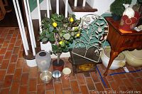 Lot contents including faux lemon tree pot, metal planters, and decorative metal chair placed near stairs with brick flooring.