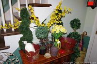 Full view of faux plants and decorative pots on a wooden table with staircase background