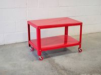 Overall view of red metal trolley showing two shelves and casters