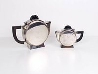 Front view of teapot and creamer showing circular bodies, wood handles, patina