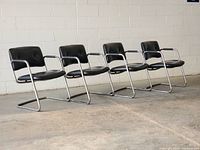 Front angled view of four black chrome cantilever chairs