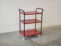 Full view of cart front left showing three shelves, frame, casters