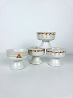 Four ceramic pedestal dessert cups arranged, showing rainbow patterns