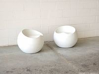 Two white fiberglass spherical chairs side by side