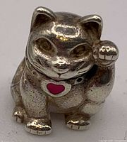 Front view of sterling silver Waving Cat charm showing facial details, raised paw and pink enamel heart