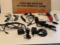 Overview of cables, chargers, adapters, voice recorder, utility knife, yard waste bag