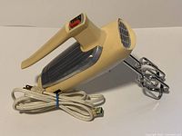 Side profile of GE hand mixer with beaters and cord visible
