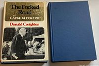 Front view of both hardcovers, dust-jacketed "The Forked Road" and plain blue "Confederation"