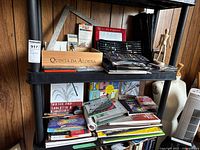 Two black plastic shelves filled with art supplies and books
