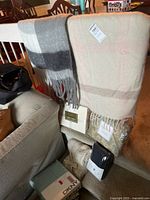 Two plaid blankets draped over rail with packaged bedding sets below