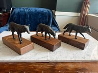 Front view of three bronze wolf sculptures on wooden bases